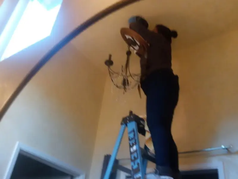 Electrician installing a chandelier in a Crafton residence